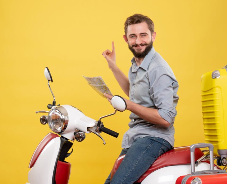 travel-concept-with-smiling-young-man-sitting-motocycle-with-suitcases-it-holding-map-yellow