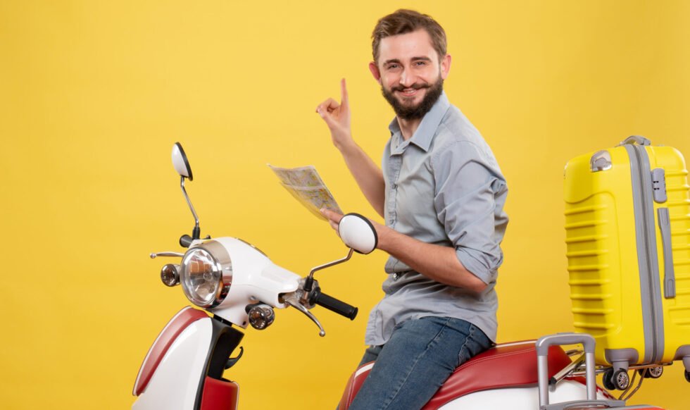 travel-concept-with-smiling-young-man-sitting-motocycle-with-suitcases-it-holding-map-yellow